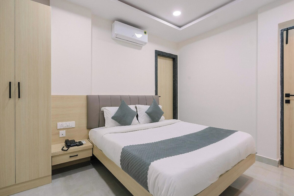 A modern bedroom with a bed, nightstand, wardrobe, and an air conditioning unit.