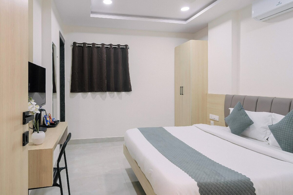 Une chambre d’hôtel moderne équipée d’un lit, d’un bureau, d’une chaise, d’une télévision et d’un appareil de climatisation.