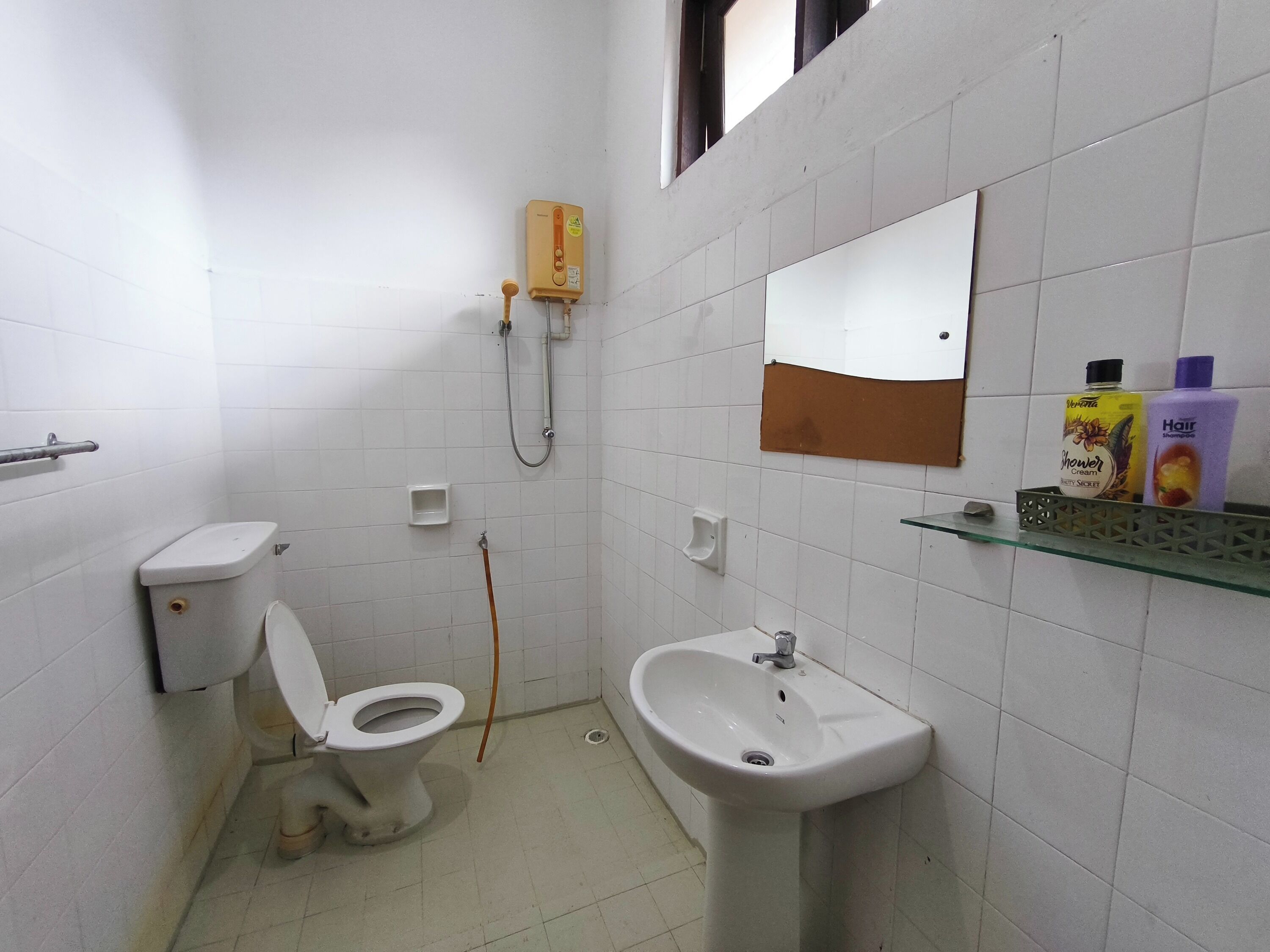 Un baño pequeño con inodoro, lavamanos y ducha.