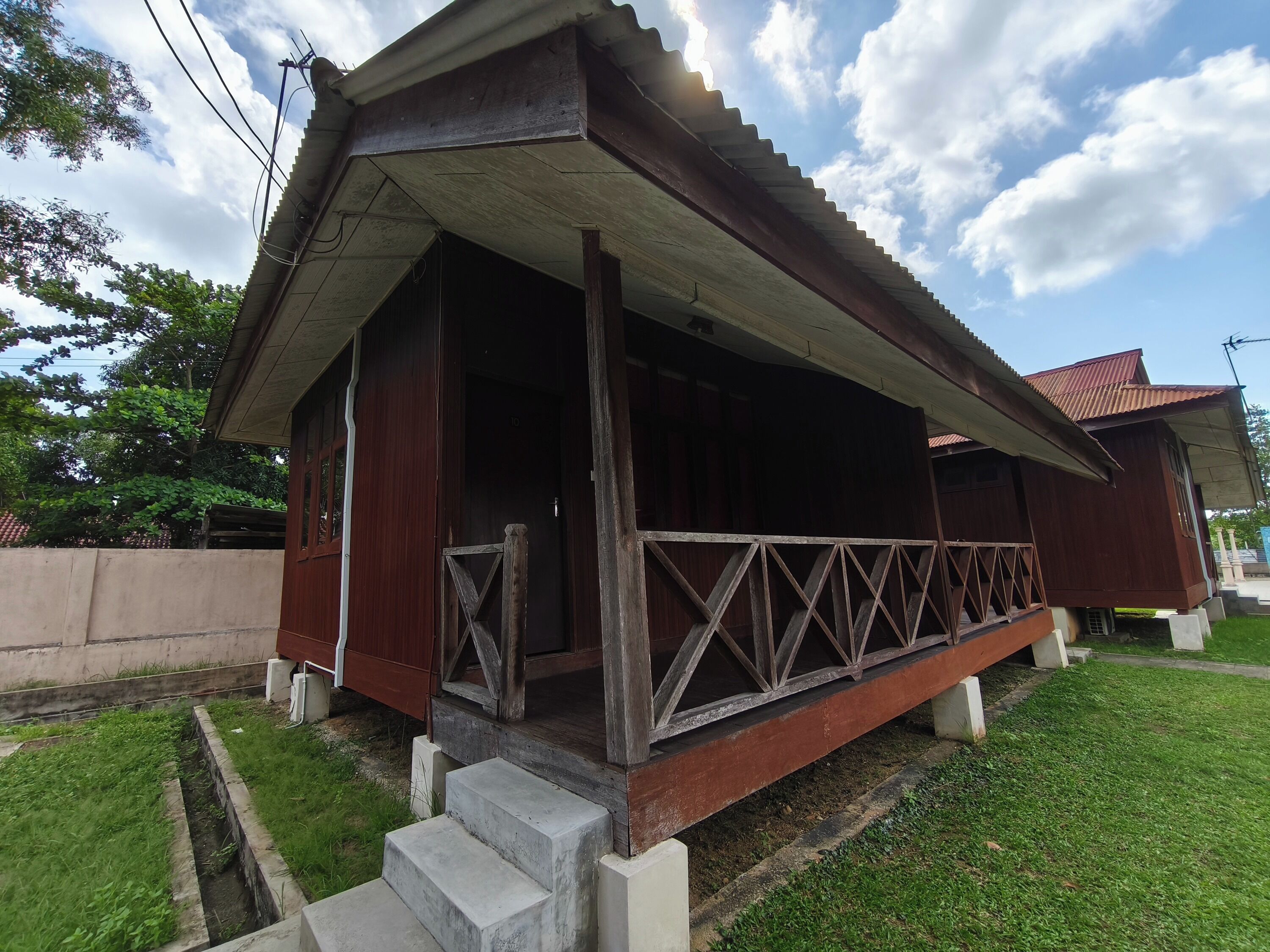 A wooden house with a porch, concrete steps, and a fenced yard.