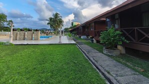 A hotel with a swimming pool, palm trees, and a clear sky. - Qurata Riverside Resort (Kuala Terengganu)