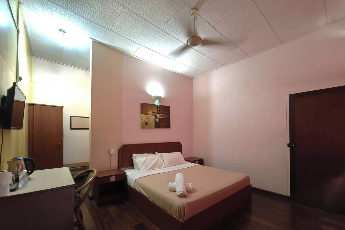 Ein Hotelzimmer mit Bett, Nachttisch und Schreibtisch mit Stuhl.