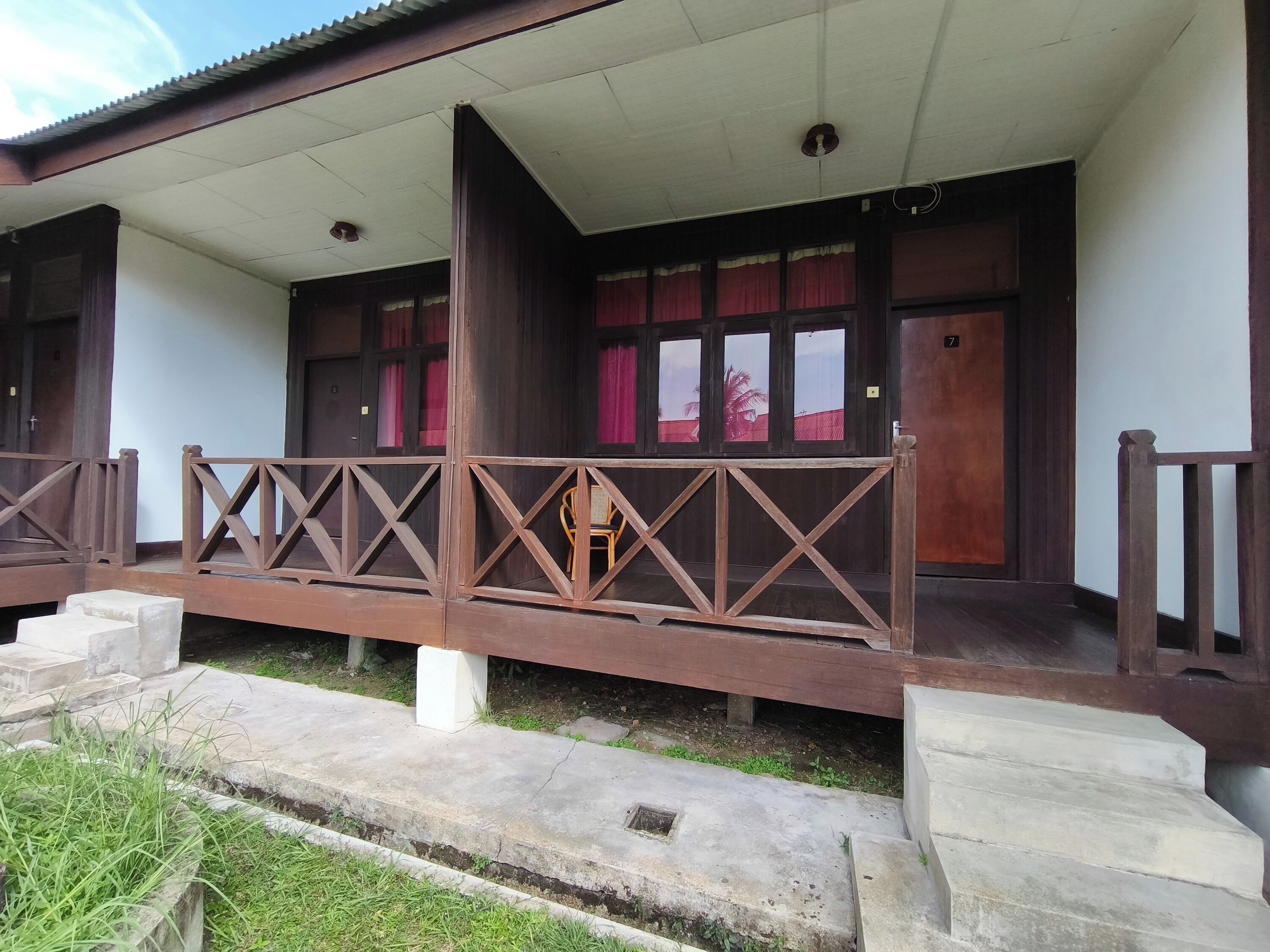 A building with a covered porch, wooden railings, and a staircase leading to the entrance.