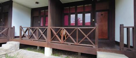 A building with a covered porch, wooden railings, and a staircase leading to the entrance.