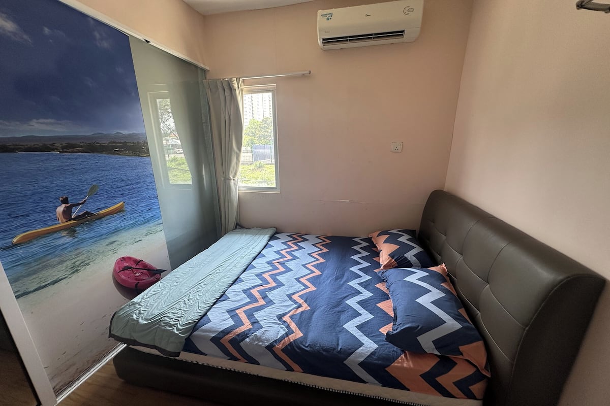 Un dormitorio con cama, ventana, equipo de aire acondicionado y vista de alguien practicando kayak.