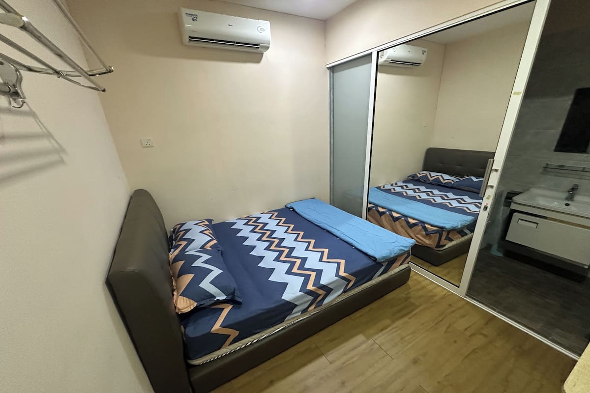Un dormitorio pequeño con cama, armario y espejo.