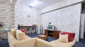 A living room with a sofa, a coffee table, a TV, and a bar area. - Vintage Inn Jonker Walk Melaka (Malacca City)
