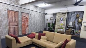 A living room with a beige sectional sofa, a wooden coffee table, and a brick wall. - Vintage Inn Jonker Walk Melaka (Malacca City)