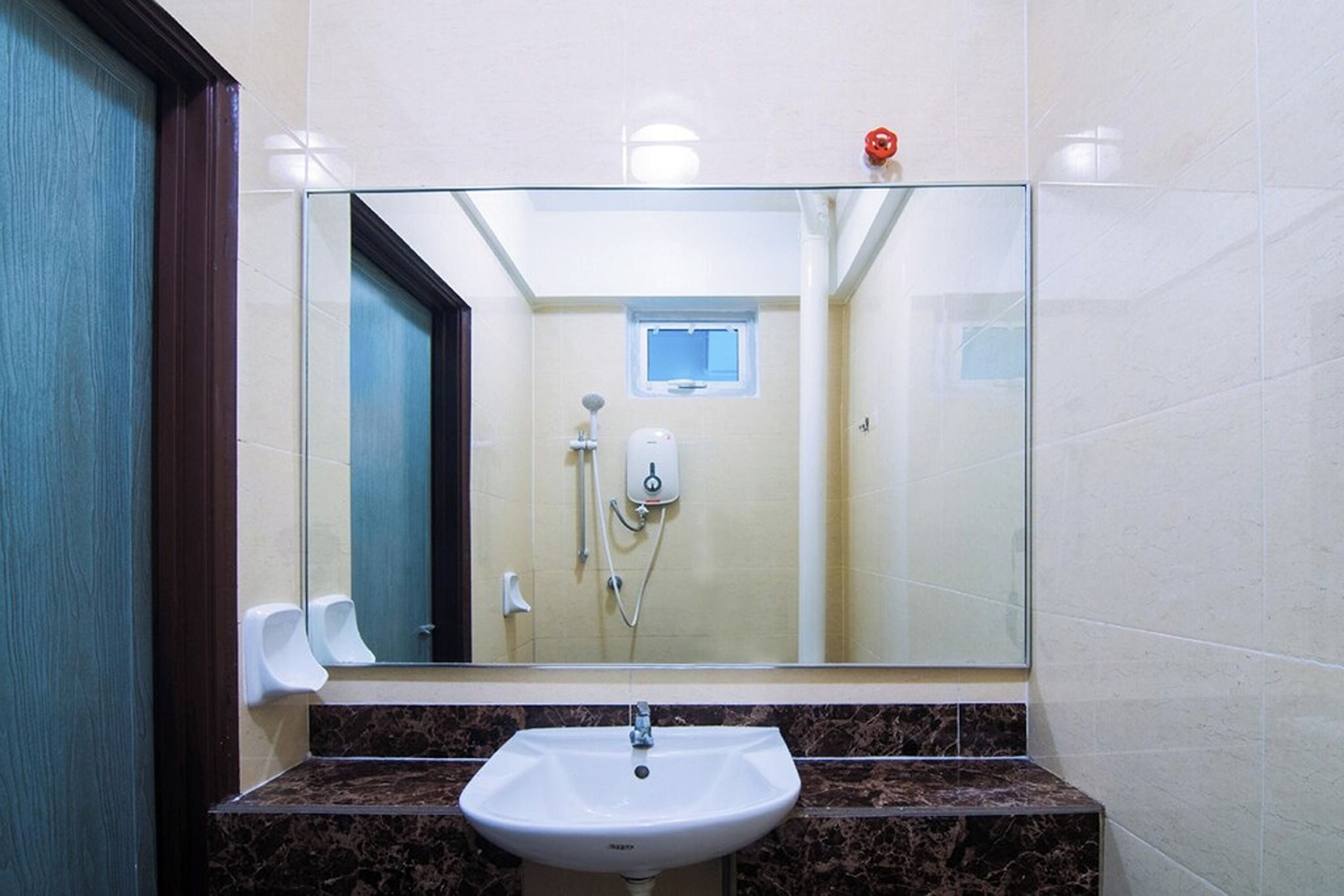 Un baño con lavamanos de mármol, cabina de ducha de vidrio y secador de manos.