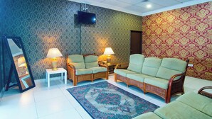 Un salon avec deux canapés, un téléviseur et un tapis à motifs.