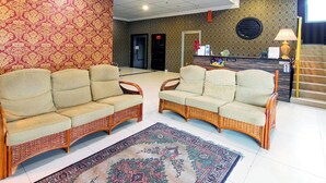 Un hall d’entrée avec deux canapés en osier, un tapis à motifs, un comptoir d’accueil et un escalier.