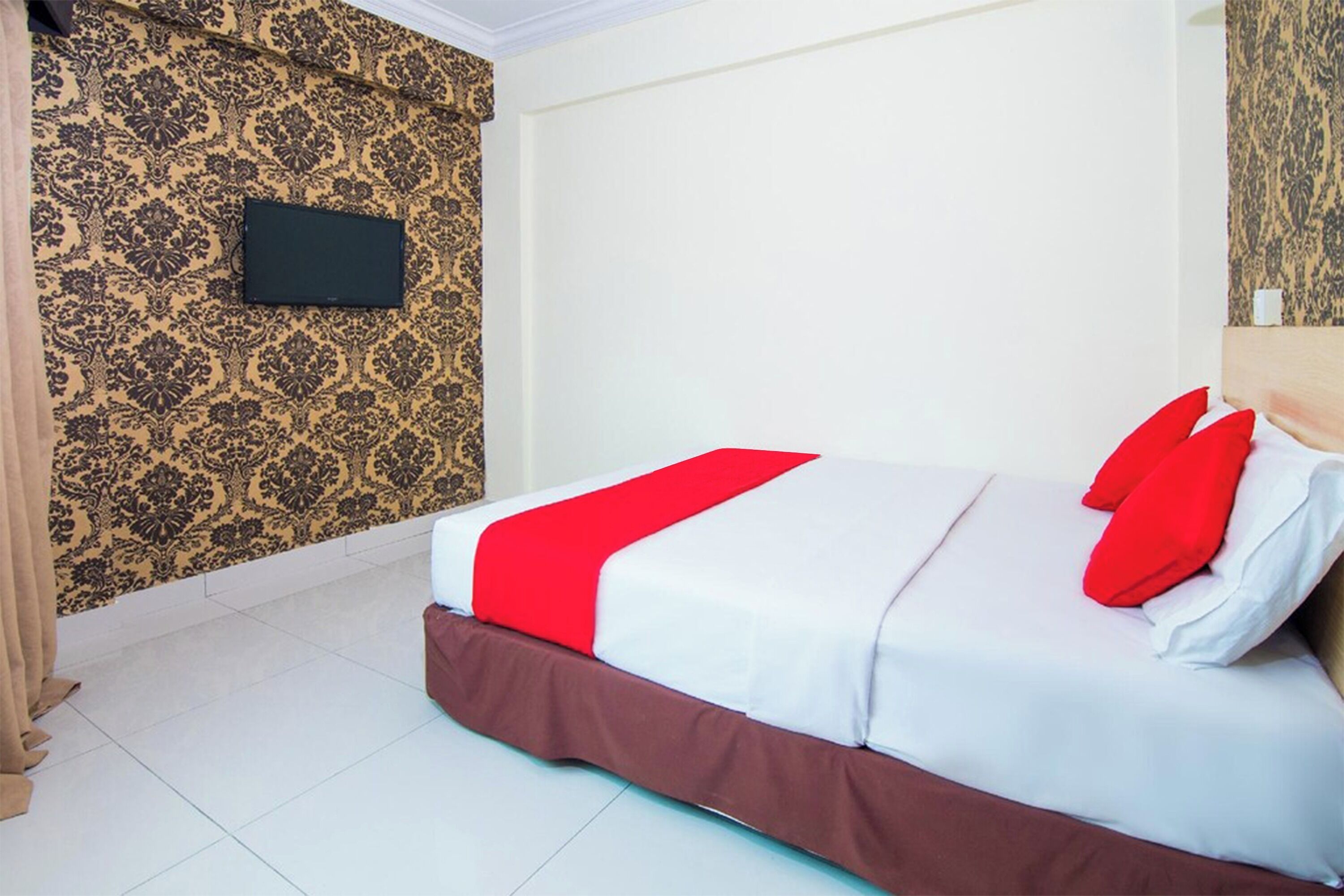 Una camera d'hotel con un letto, una TV a muro e carta da parati decorata.