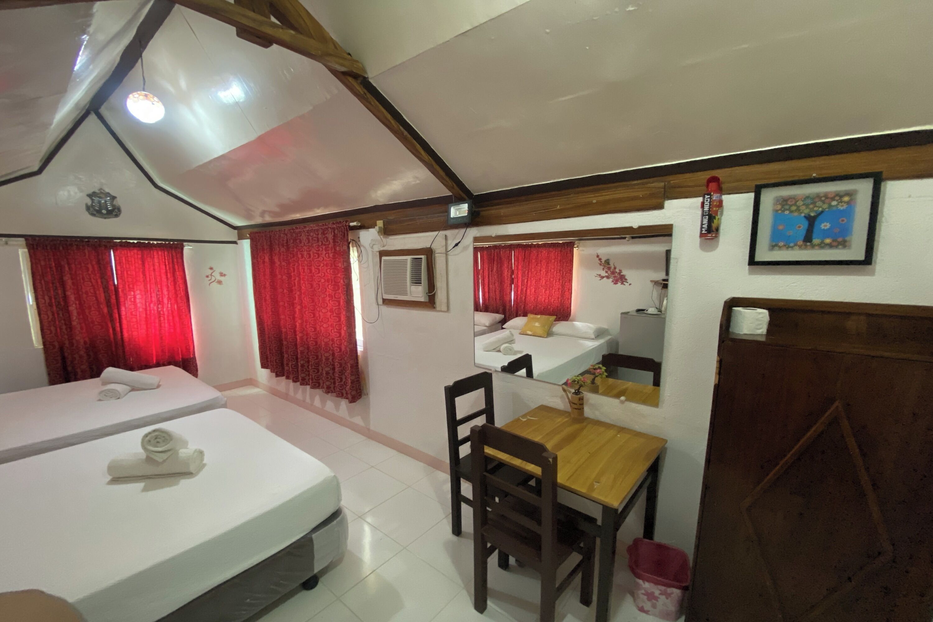 Una camera d'albergo con due letti, un tavolo da pranzo in legno e un angolo cottura.
