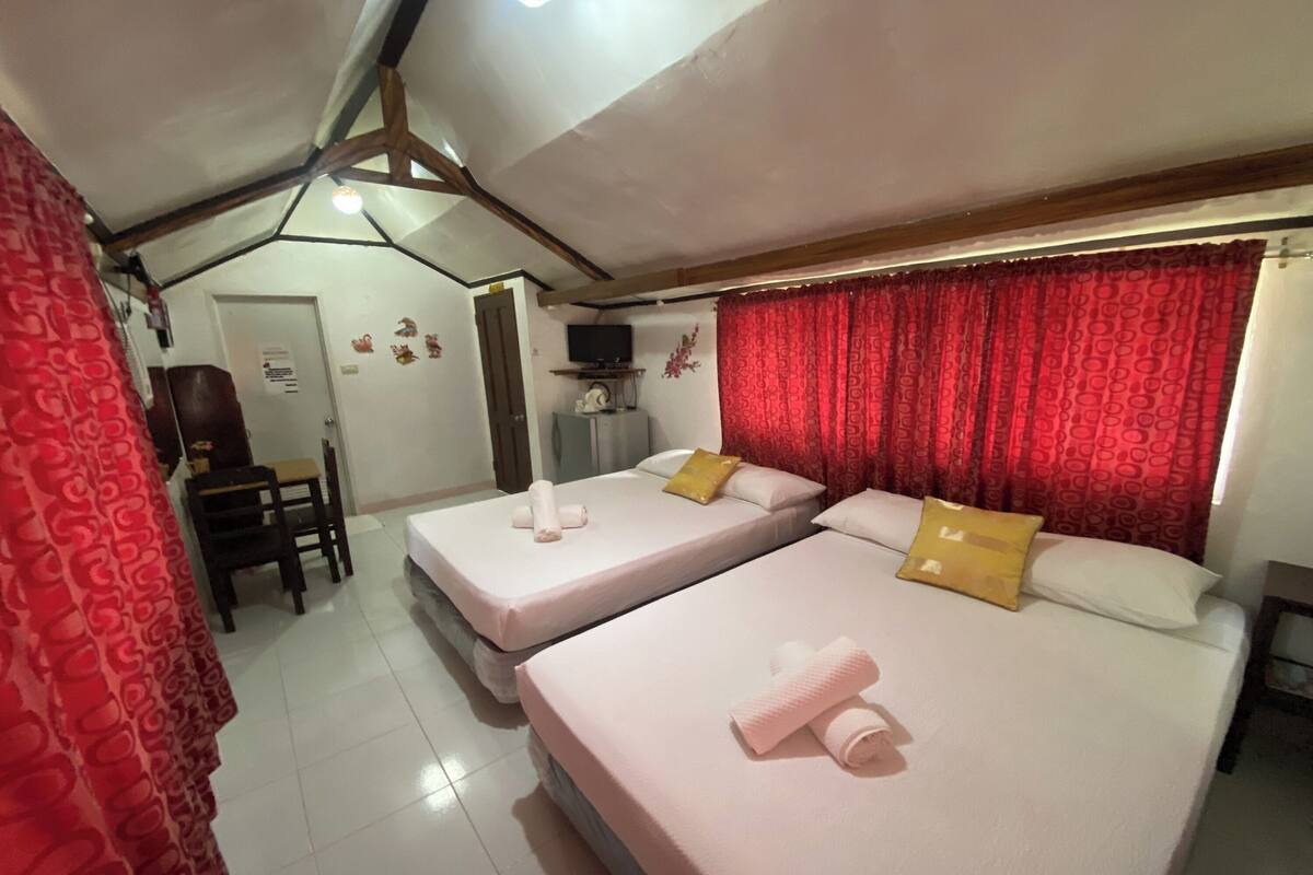 A hotel room with two beds, a TV, and a desk.