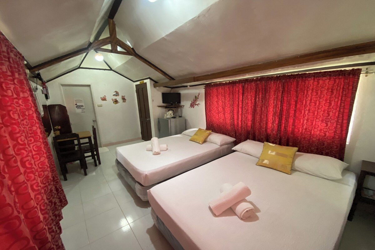 A hotel room with two beds, a TV, and a desk.