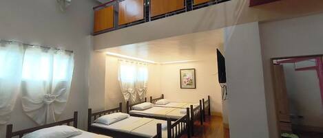 Un dormitorio con literas, un televisor pequeño y una ventana con cortinas.
