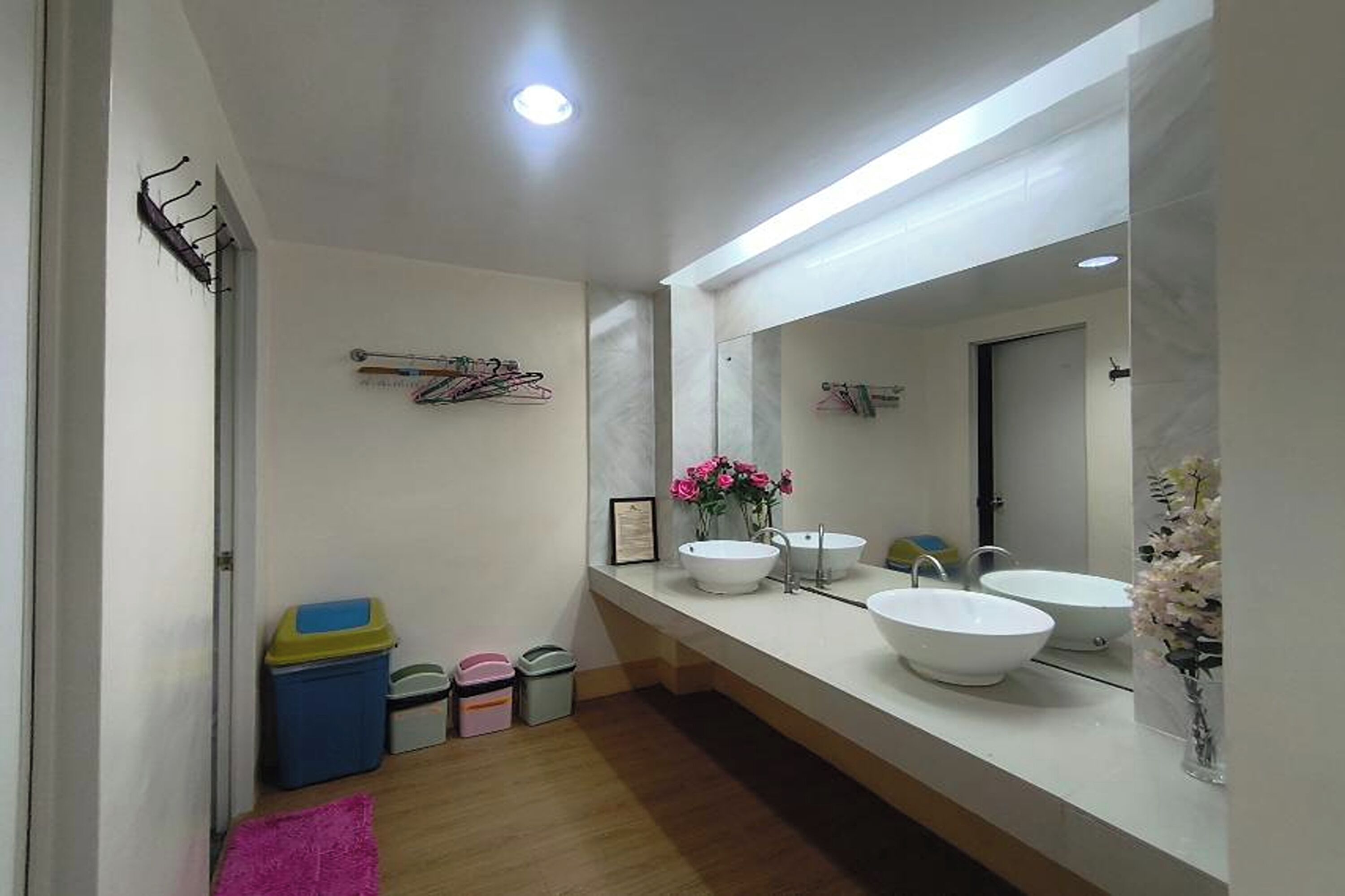 A modern bathroom with two sinks, a large mirror, and a wooden floor.