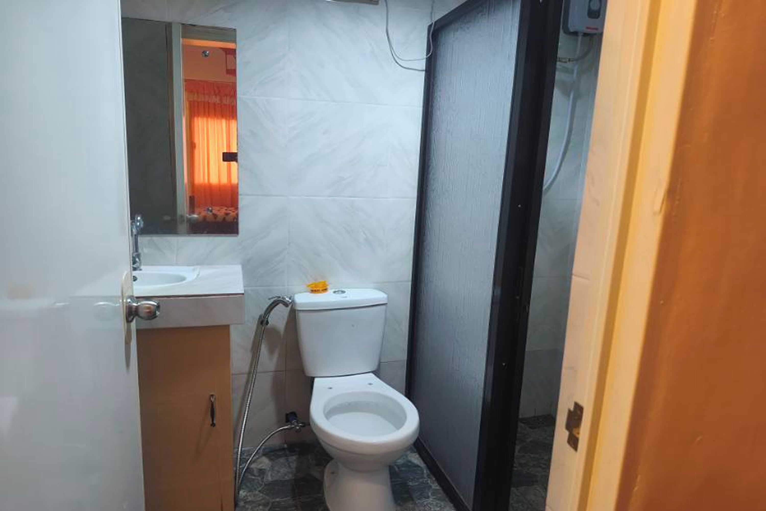 A small bathroom with a toilet, sink, and mirror.