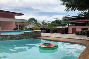 Una piscina con un cerchio galleggiante, circondata da un muro in pietra e piante in vaso.