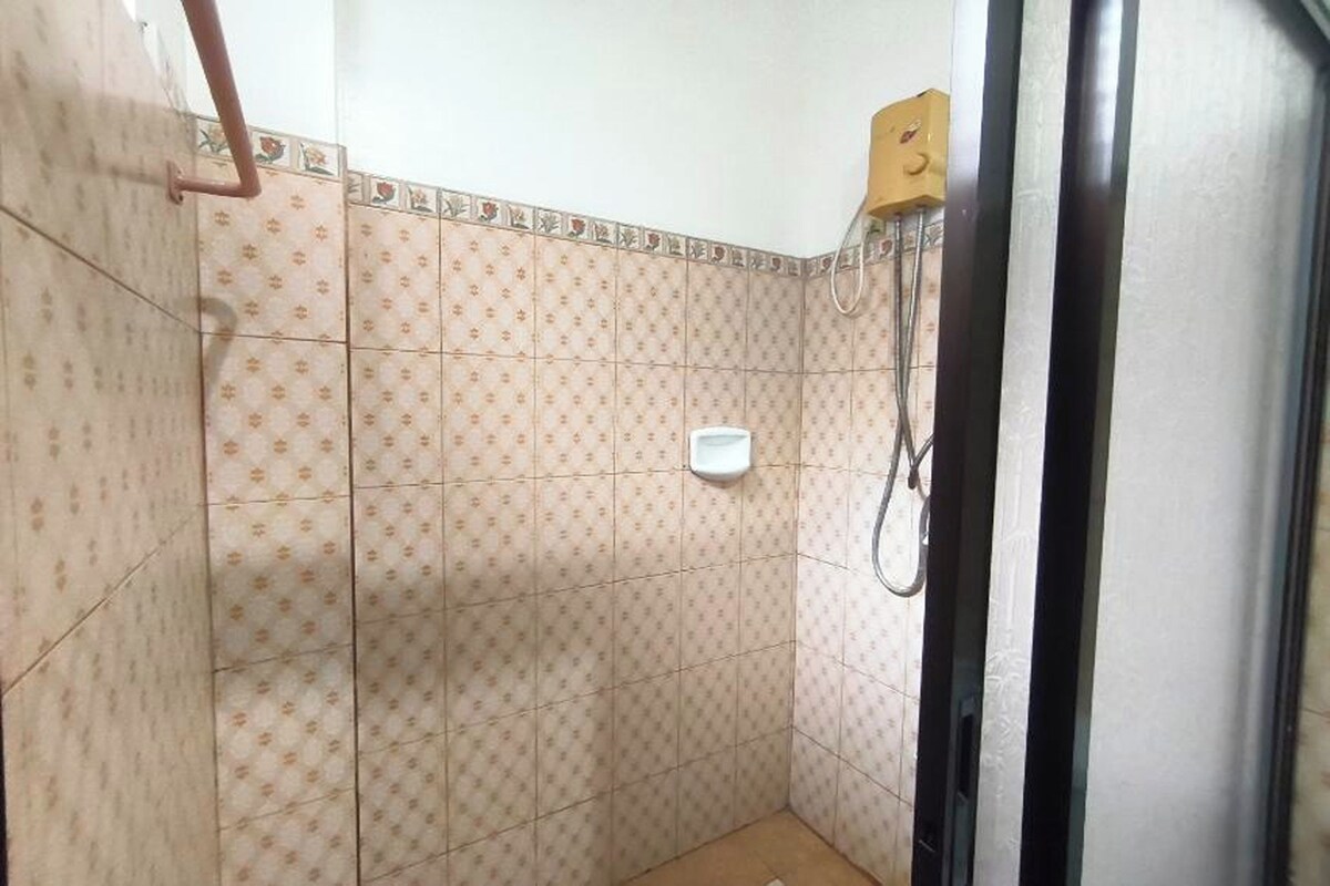 Ein kleines Badezimmer mit Fliesen, einer Dusche, einer Toilette und einem Händetrockner.