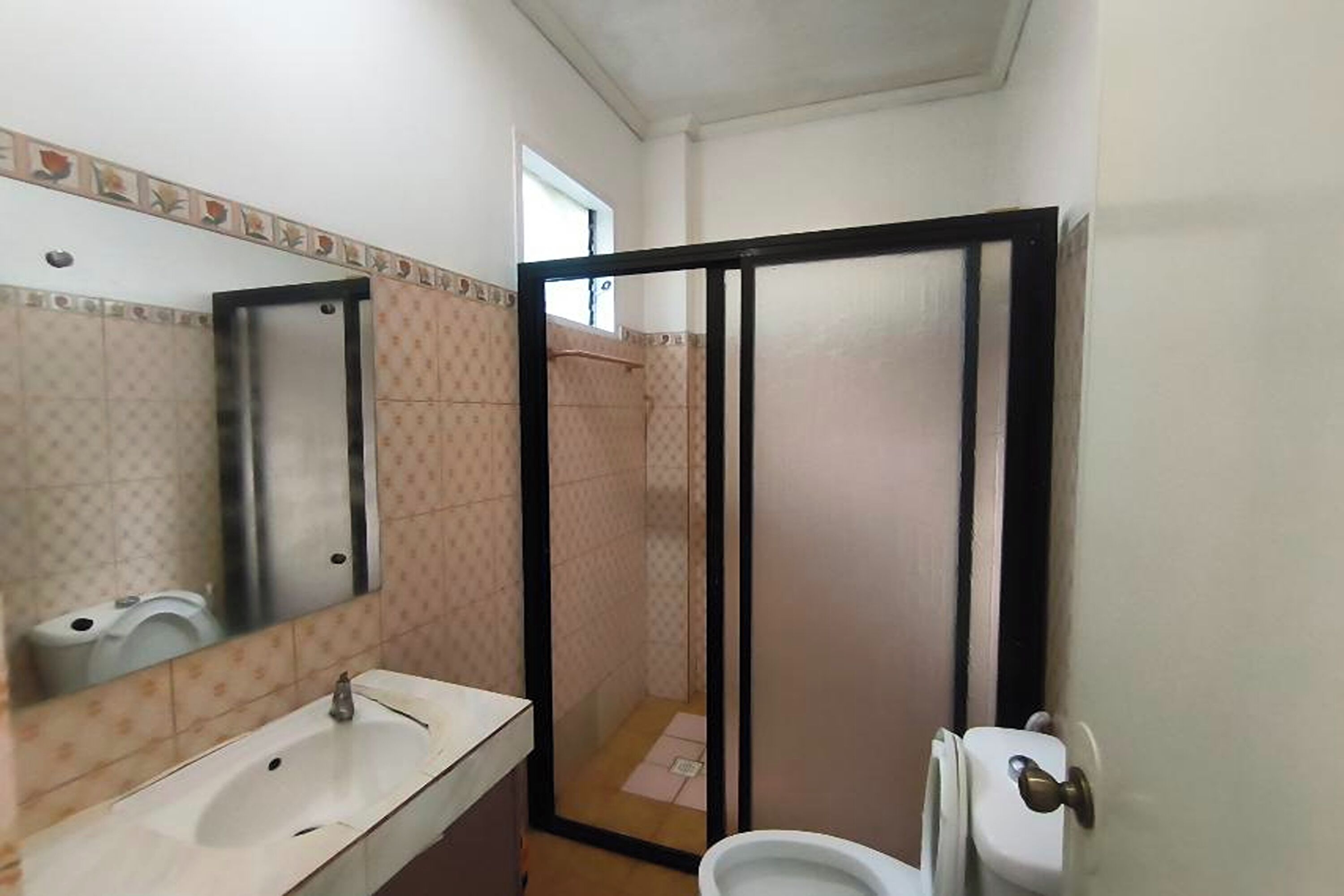 A bathroom with a sink, mirror, toilet, and shower enclosure.