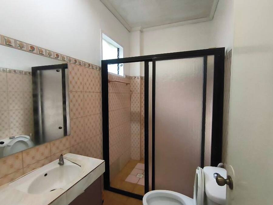 A bathroom with a sink, mirror, toilet, and shower enclosure.
