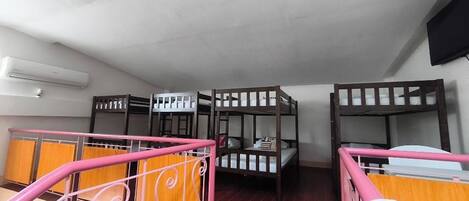 Un dormitorio con literas, barandilla rosa y ventilador de techo.