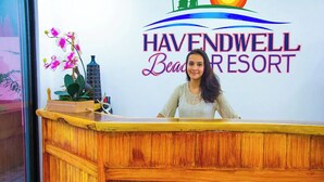 Bancada de recepção no Havendwell Beach Resort, com logotipo e uma orquídea em vaso.