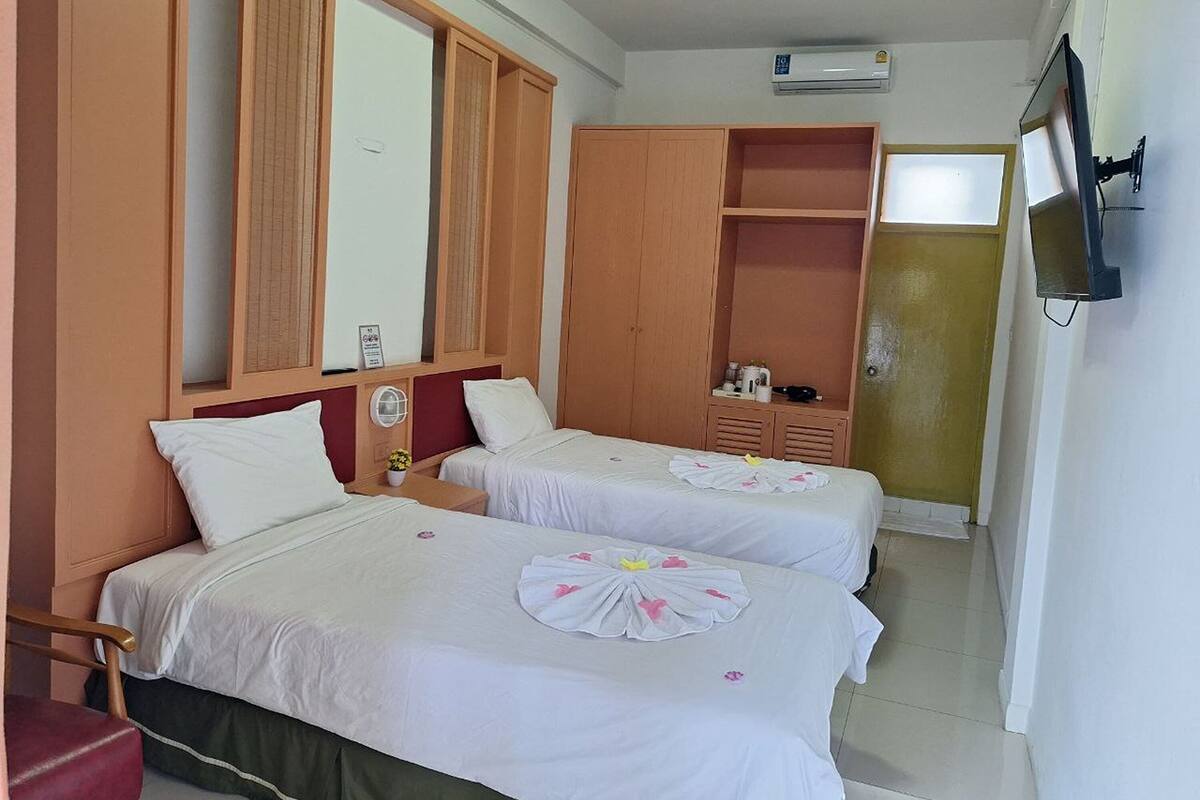 Een hotelkamer met twee bedden, een kledingkast, een televisie en een airconditioning.