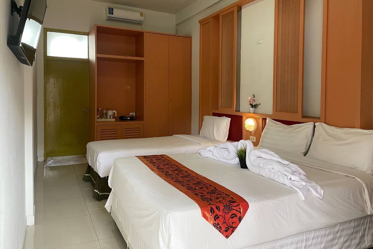 Een hotelkamer met een groot bed, een kledingkast, een spiegel en een televisie.