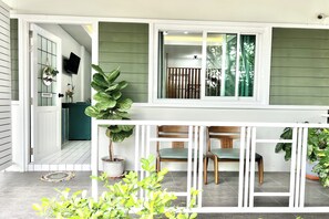 A house with a porch, a dining area with chairs, and a potted plant. - Bann Kam B&B (Krabi)