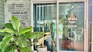 A house entrance with a welcome sign, a potted plant, and a sign listing family values. - Bann Kam B&B (Krabi)