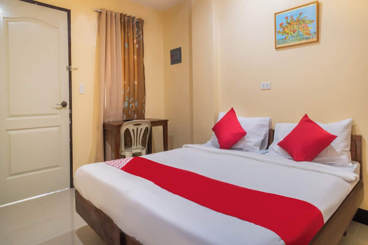 Una habitación de hotel con cama, escritorio, silla y puerta.