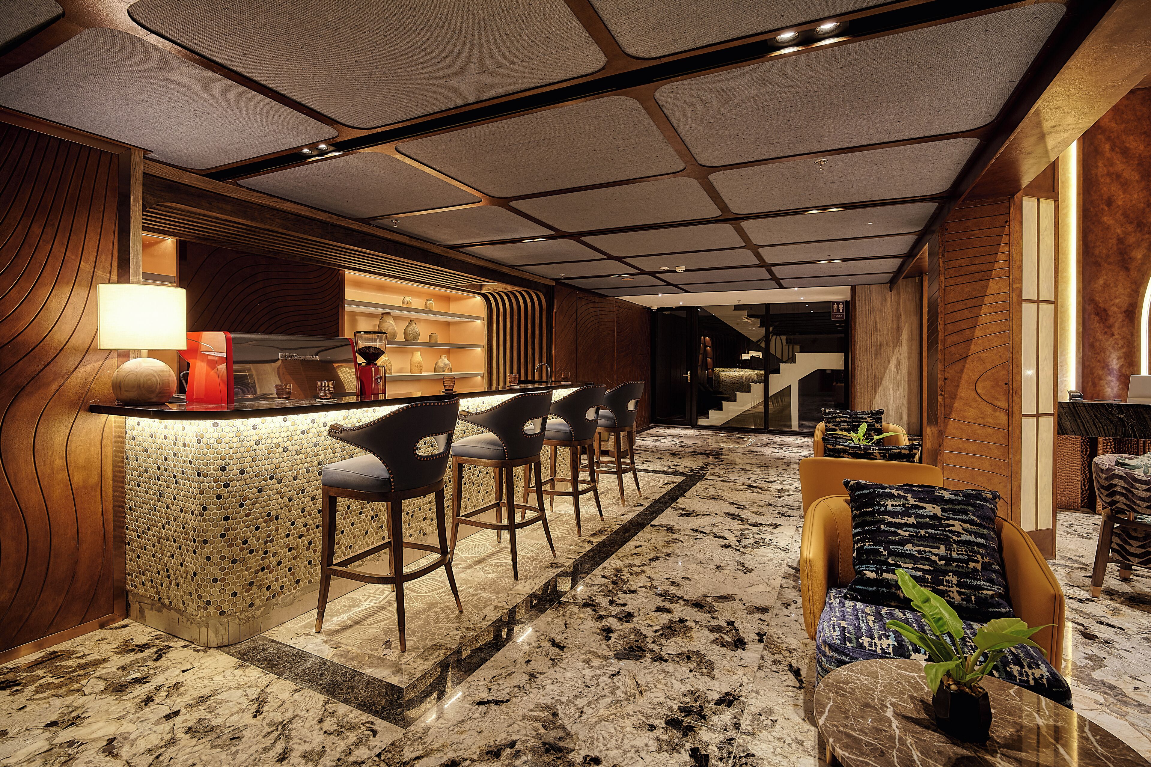 A modern bar area with a marble floor, bar stools, and a counter with a lamp.