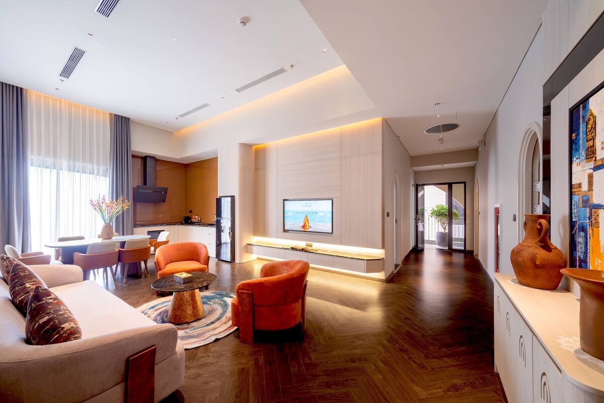 A modern living room with a sofa, armchairs, a coffee table, and a TV.