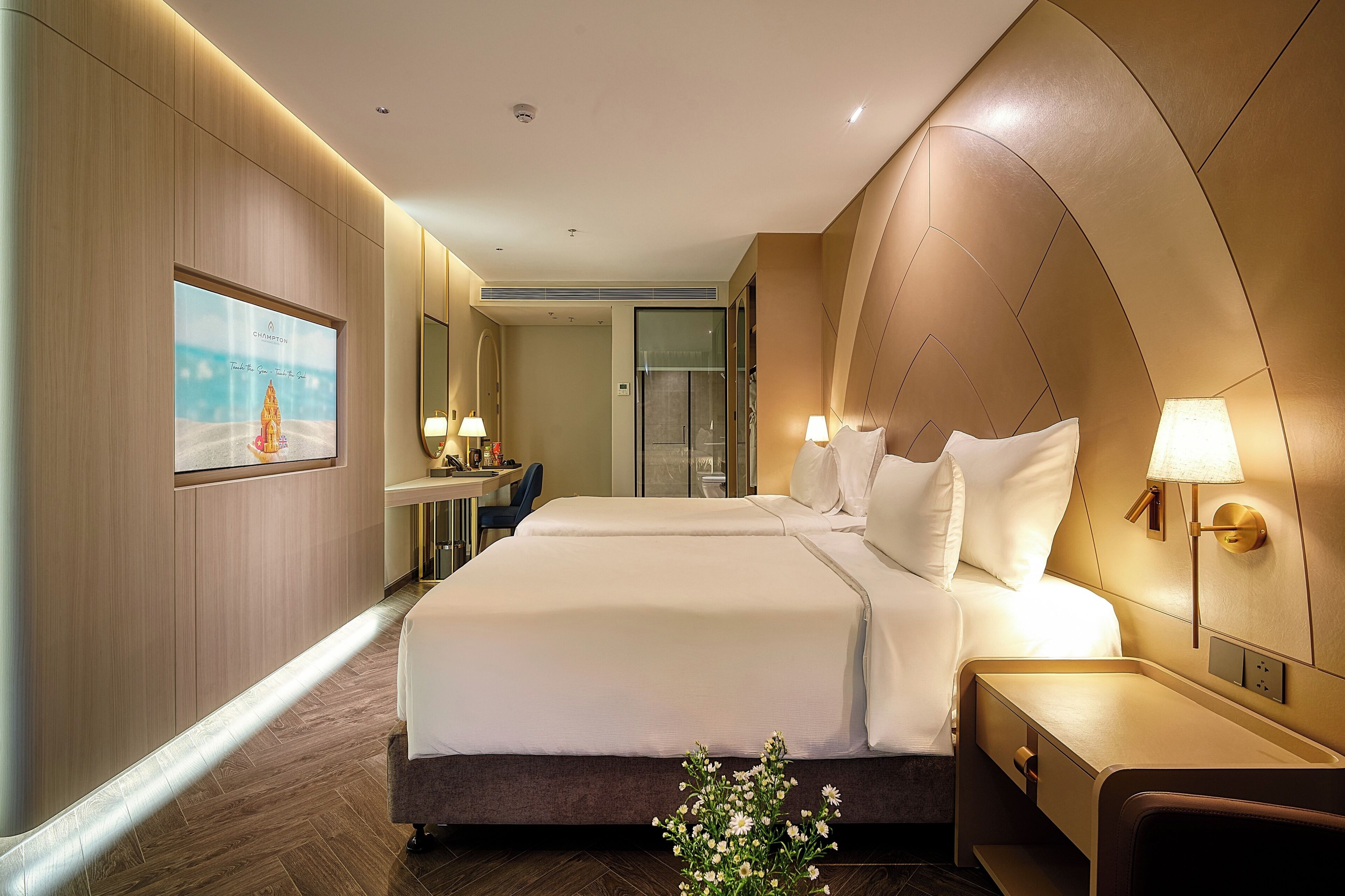 Une chambre d’hôtel avec un grand lit, des tables de chevet avec des lampes, un bureau avec une chaise et un grand miroir.