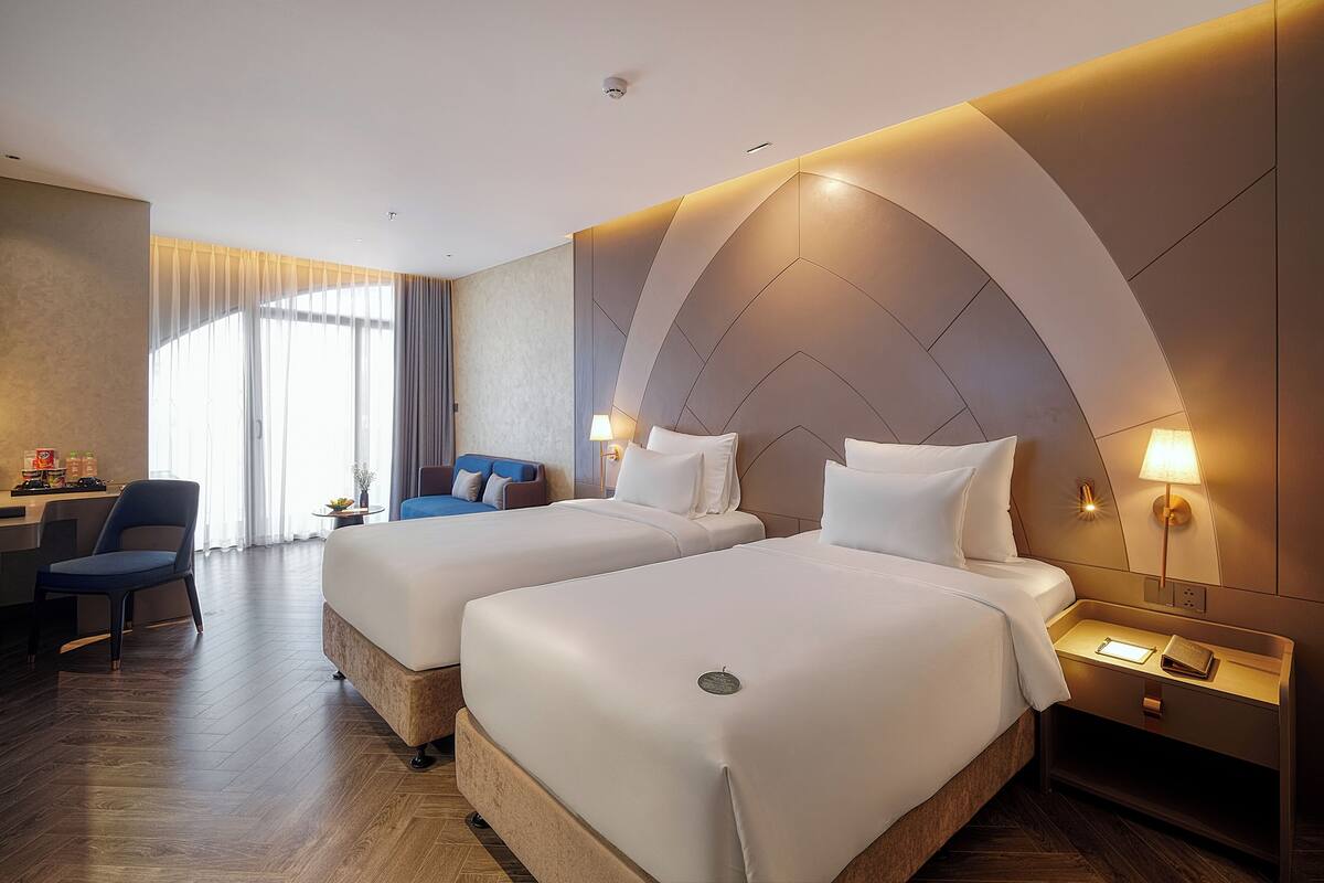 A hotel room with two beds, a desk, and a chair.