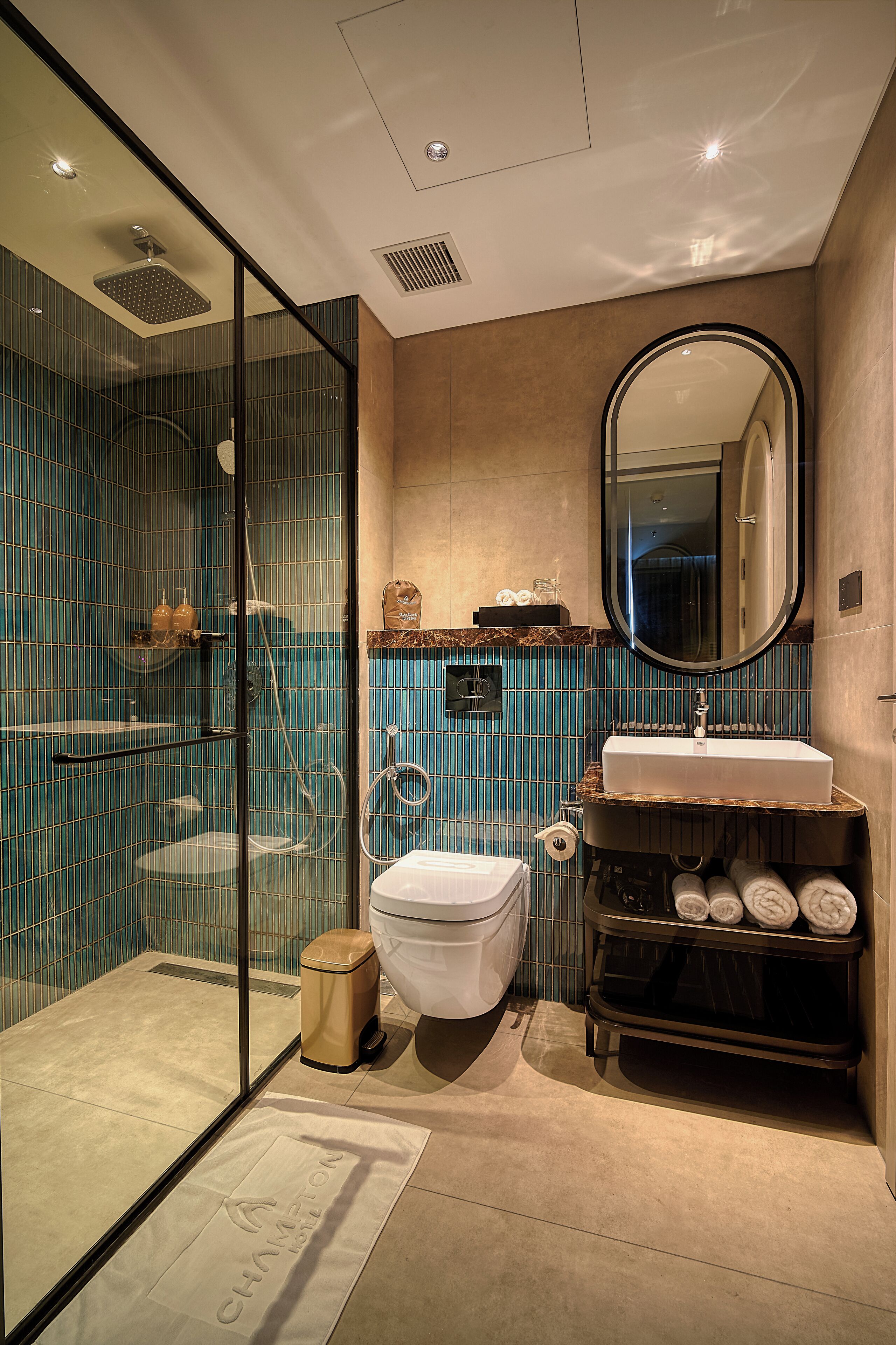 Un baño moderno con ducha de vidrio, inodoro blanco, lavamanos con encimera de mármol y un espejo grande.