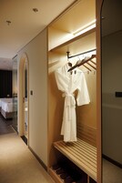 Quarto de hotel com closet amplo, uma cama e um banco com sapatos.