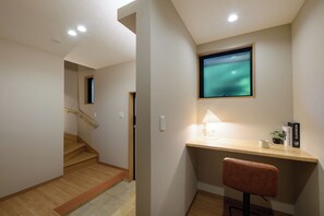 Een modern interieur met een houten bureau, een stoel, een aan de muur bevestigde televisie en een trap.
