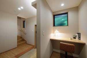 Un interior moderno con un escritorio de madera, una silla, un televisor montado en la pared y una escalera.