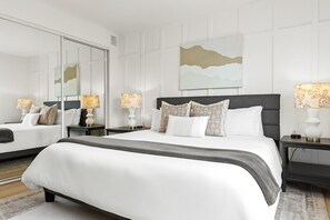 Een moderne hotelkamer met een groot bed, twee nachtkastjes, een grote spiegel en een schilderij aan de muur.