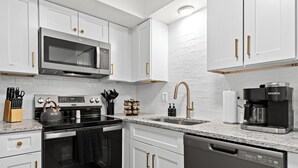 A modern kitchen with white cabinetry, stainless steel appliances, and a granite countertop. - Charming 1BR Getaway with King Bed in Royal Oak (Royal Oak)