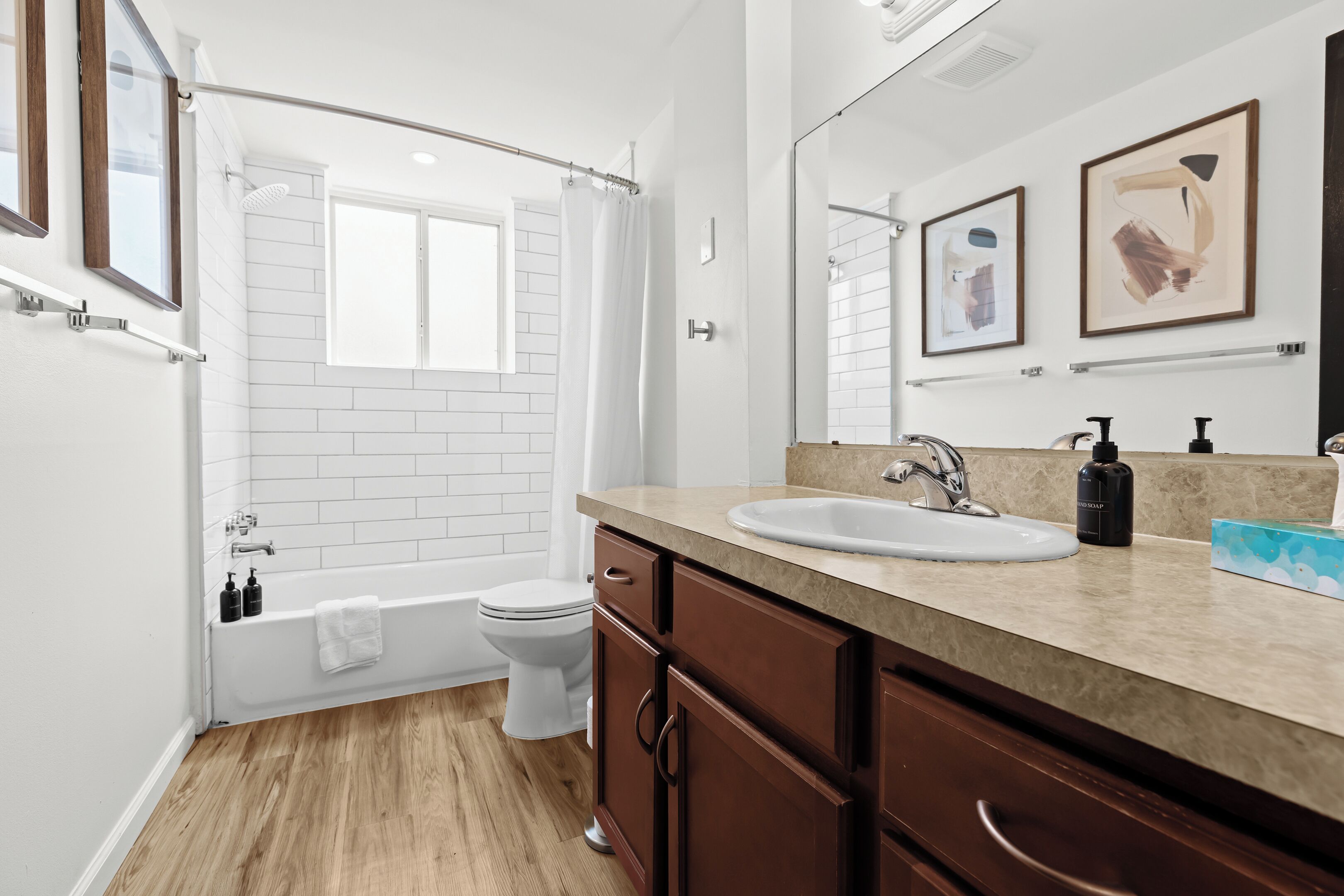 Freshen up in a sparkling clean bathroom featuring a deep soaking tub, rain shower head, soft white towels, and stylish wall art.