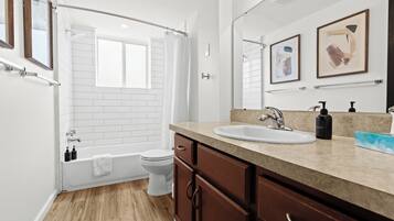 Freshen up in a sparkling clean bathroom featuring a deep soaking tub, rain shower head, soft white towels, and stylish wall art.