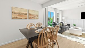 Un espace repas moderne avec une table noire et des chaises en bois, un canapé gris et une table basse blanche.