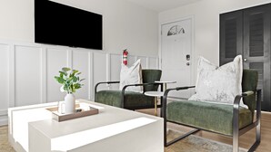 Un salon moderne avec un comptoir d’accueil blanc, des fauteuils verts à revêtement en tissu, un téléviseur à écran plat fixé au mur et un extincteur sur la porte.