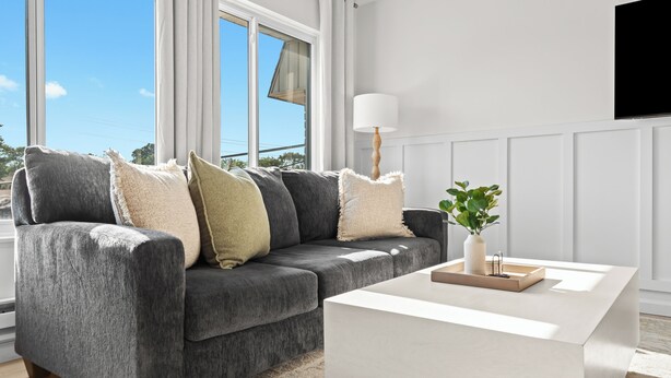Un salon moderne avec un canapé gris, une table basse blanche et une plante en pot.
