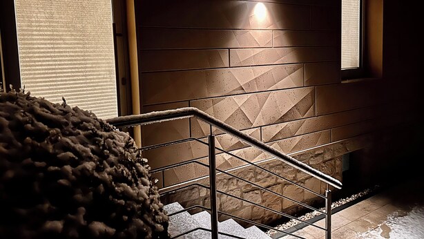 A staircase with metal railings and a textured wall with geometric patterns. - Studio apartment "Cozy" with terrace & parking space (Blankenburg)