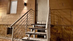 A staircase with a metal railing and carpeted steps, leading to a door with a window above it. - Studio apartment "Cozy" with terrace & parking space (Blankenburg)